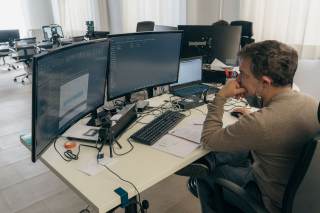 Uomo che lavora in una postazione con diversi monitor del computer.