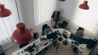 Persone che lavorano in ufficio alle proprie postazioni con monitor dei computer.