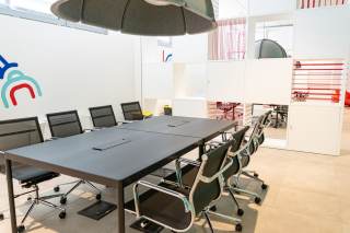 Sala con un grande tavolo e sedie per lavorare e installazioni di design sul muro.