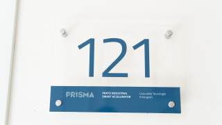 Cartello affisso a muro con il numero 121 e il nome "PRISMA".